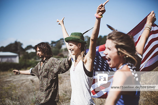Three cheering hippies with US flag in the nature