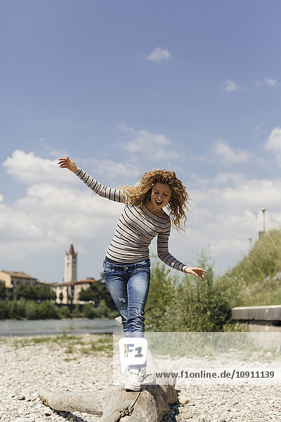 Italy  Verona  woman balancing on dead wood at riverside