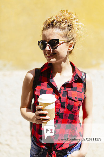Smiling young woman with coffee to go