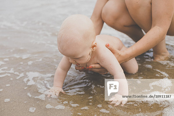Mother and baby boy playing in the water at the beach