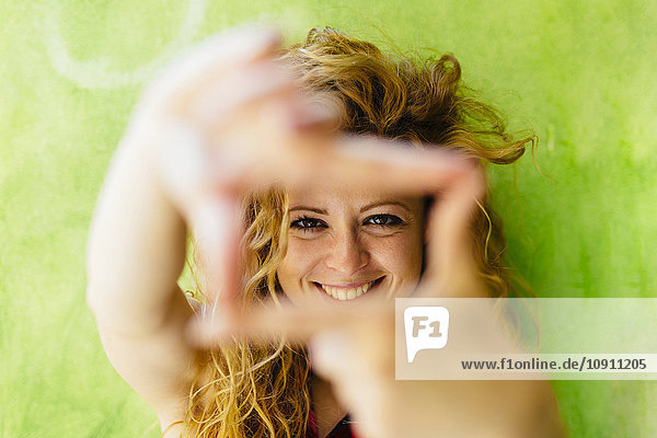 Porträt einer lächelnden Frau beim Formen eines Fingerrahmens