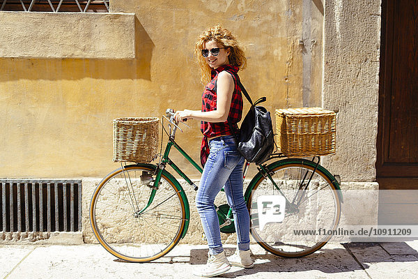 Smiling woman with bicycle in nan alley