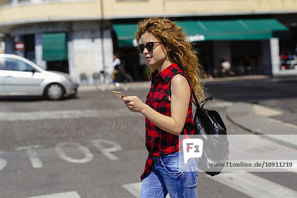 Italien  Verona  Frau  die die Straße überquert und auf das Handy schaut.