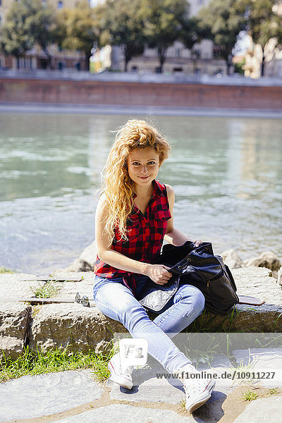 Italien  Verona  lächelnde Frau am Flussufer sitzend