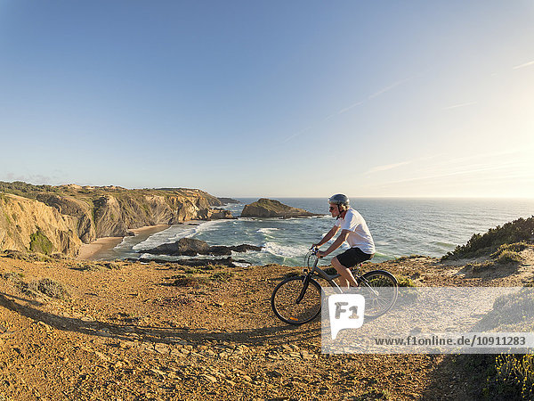 Portugal  Senior man mountain biking at the sea