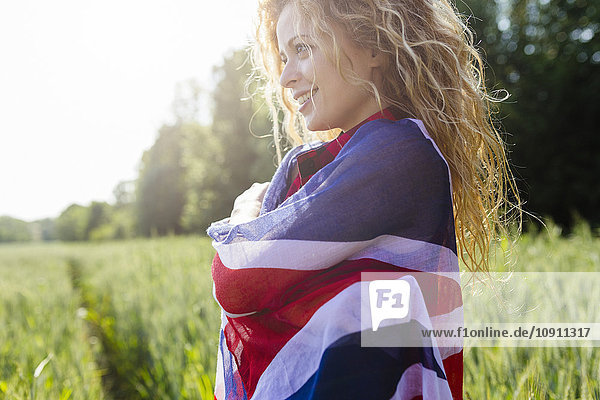 Porträt einer lächelnden Frau mit Union Jack in der Natur