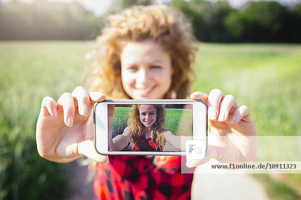 Selfie der lächelnden Frau auf dem Display ihres Smartphones