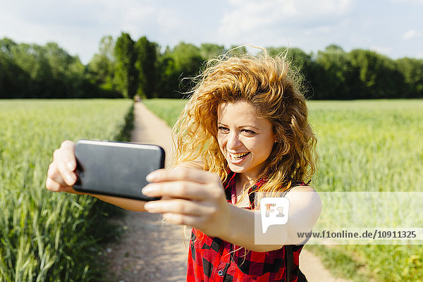 Frau nimmt Selfie mit Smartphone in der Natur