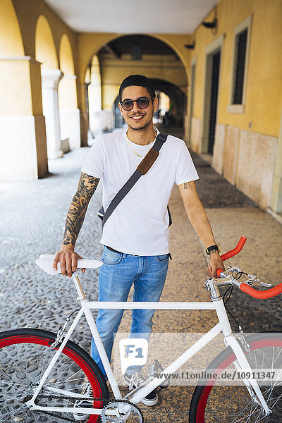 Junger Mann mit Fahrrad in der Stadt