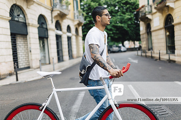 Young man walking with a bicycle in the city
