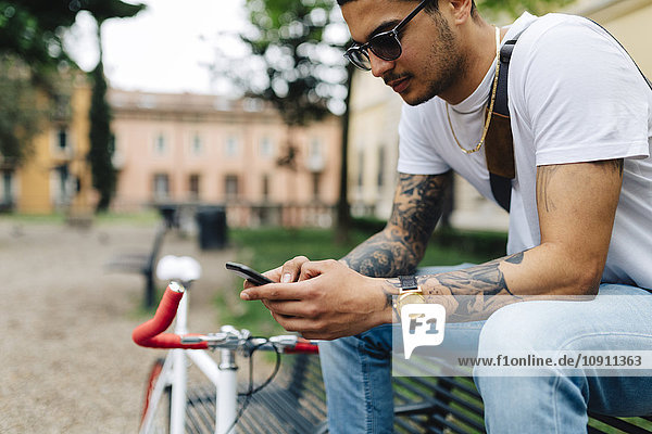 Young man sitting on bench looking at cell phone