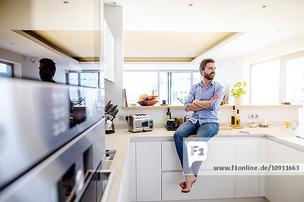Man sitting in kitchen with arms crossed