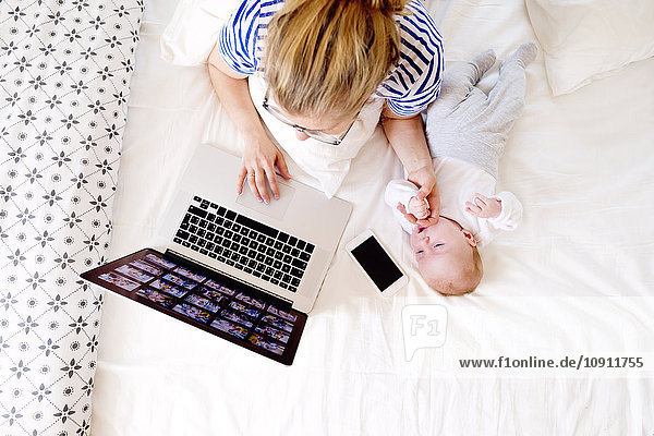 Mother with baby at home working with laptop