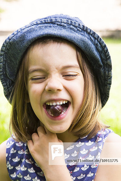 Porträt eines kleinen Mädchens mit Stachelbeere im Mund