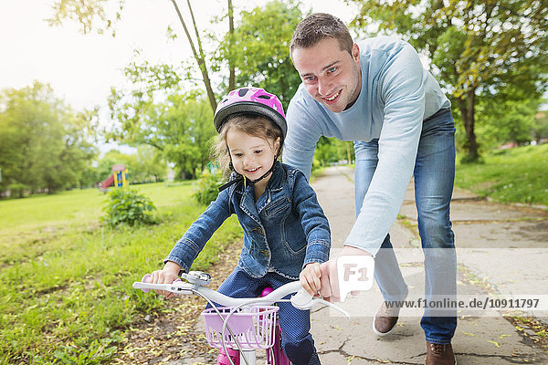 Father accompanying daughter on bike