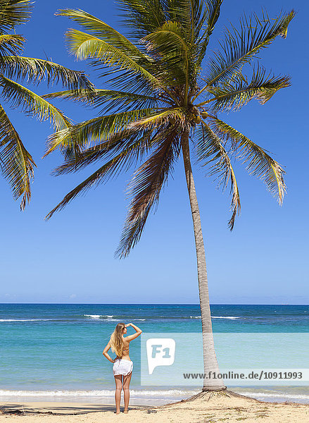 Dominikanische Rebublik  Junge Frau mit Blick auf den tropischen Strand