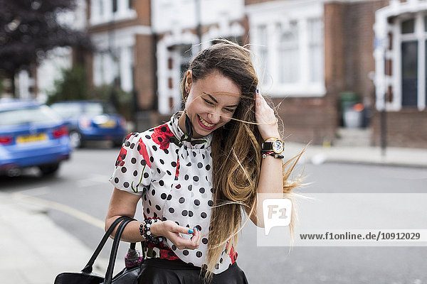 UK  London  Porträt einer lächelnden jungen Frau mit wehendem Haar
