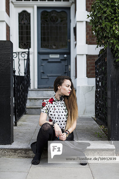UK  London  junge Frau sitzt auf einem Bürgersteig