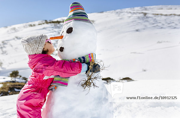 Mädchen spielen mit Schneemännern im Winter
