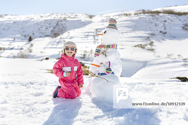 Mädchen spielen mit Schneemännern im Winter