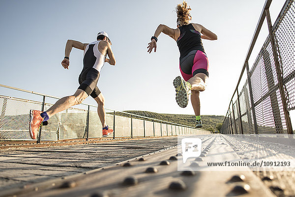Zwei Athleten laufen auf einer Brücke