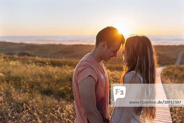 Romantic young couple embracing on the beach at sunset