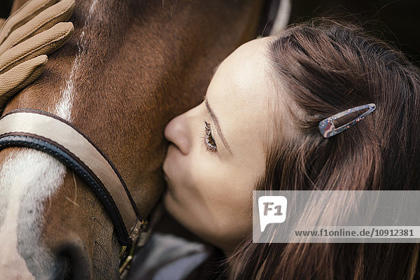 Junge Frau küsst braunes Pferd