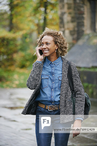 Porträt einer lächelnden Frau beim Telefonieren mit dem Smartphone