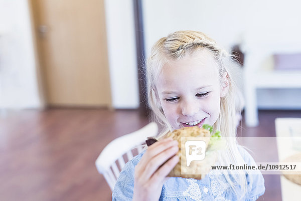 Smiling girl eating bread roll