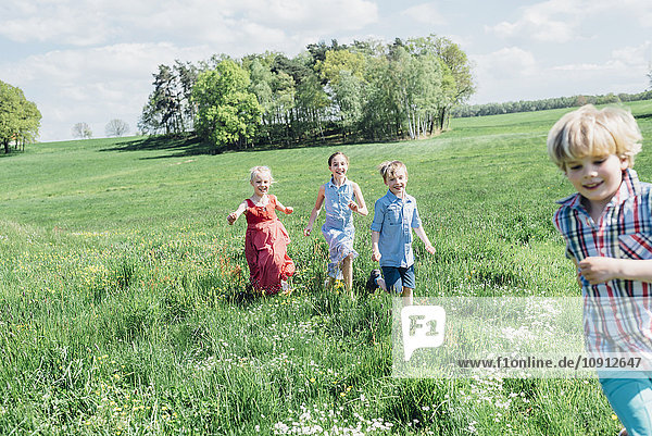 Happy children running and playing in meadow