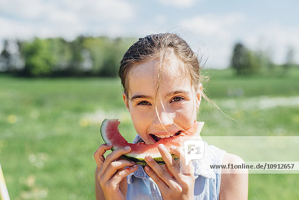 Porträt eines Mädchens im Freien  das eine Scheibe Wassermelone isst.