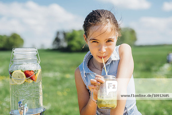 Girl outdoors drinking from jar