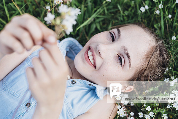 Lächelndes Mädchen auf Blumenwiese liegend
