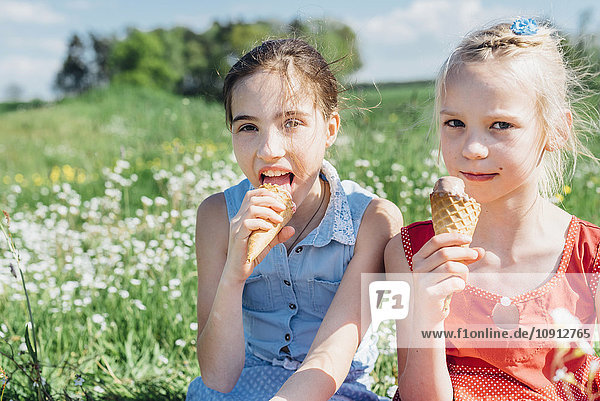 Two girls in meadow eating ice cream cones