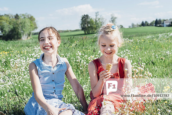 Two girls in meadow with ice cream cone