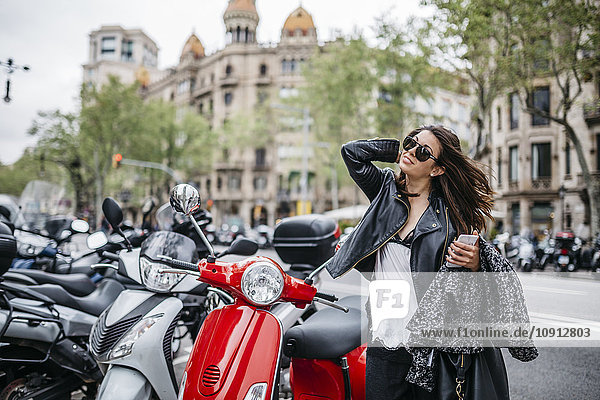Spanien  Barcelona  junge Frau in der Stadt neben geparkten Motorrollern