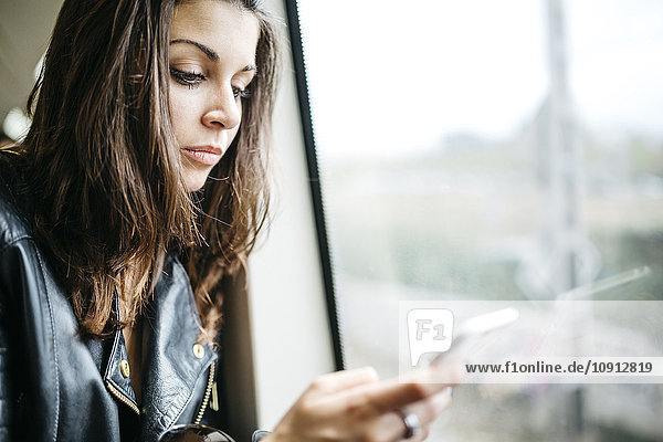 Junge Frau im Zug mit Blick aufs Handy