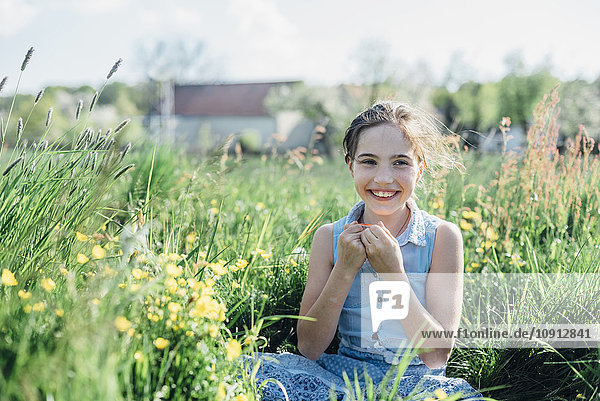 Smiling girl sitting in flower meadow