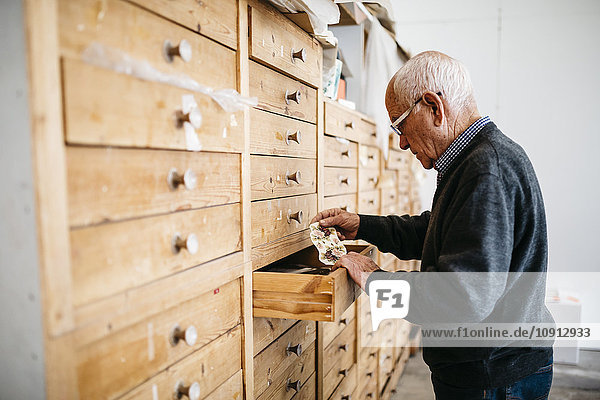 Senior Mann auf der Suche nach Abziehbildern für Keramik
