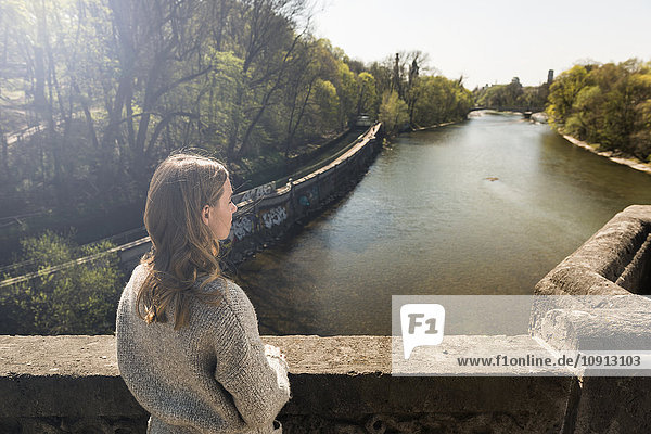 Young woman on bridge looking at river