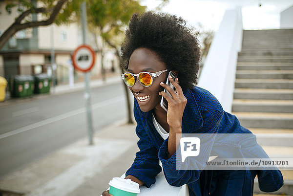 Portrait of young woman wearing mirrored sunglasses talking on mobile phone