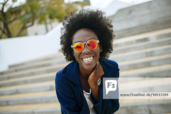 Portrait of happy young woman with nose piercing wearing mirrored sunglasses