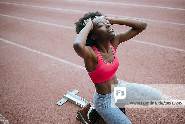Junge schwarze Sportlerin bereitet sich auf das Rennen im Stadion vor
