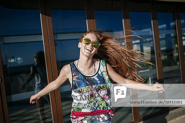 Portrait of laughing redheaded young woman with mirrored sunglasses