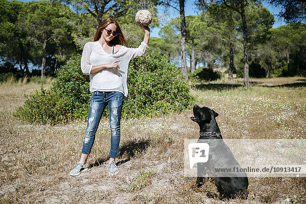 Junge Frau spielt mit ihrem Hund mit einem Ball.