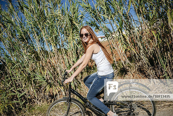 Happy young woman riding bicycle in the countryside