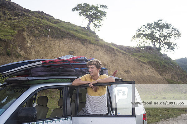 Indonesia  young surfer standing at his car