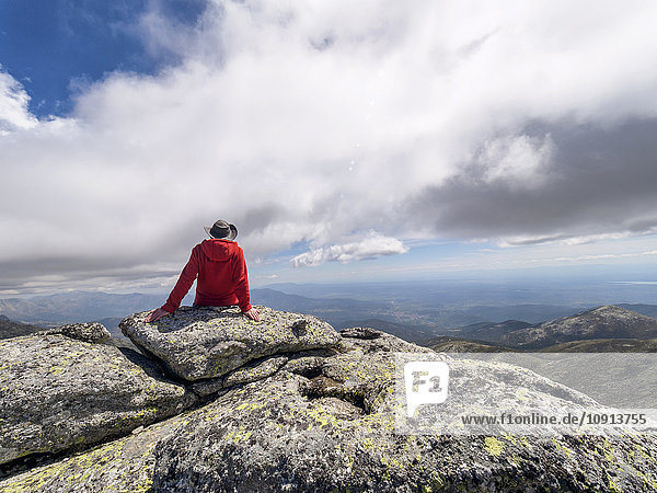 Spanien  Sierra de Gredos  Wanderer auf Felsen in der Berglandschaft sitzend