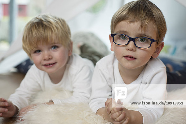 Two little boys playing at home  lying on sheepskin