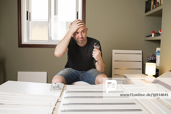 Man assembling furniture at home  looking desperate